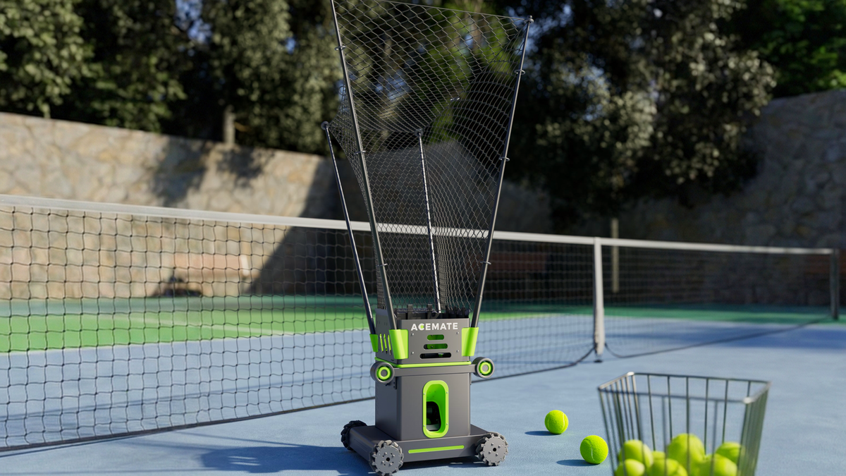 Acemate tennis robot beside a basket of tennis balls on a hard court