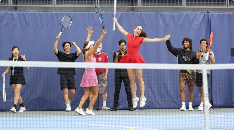 Tennis players celebrating together on an indoor court.